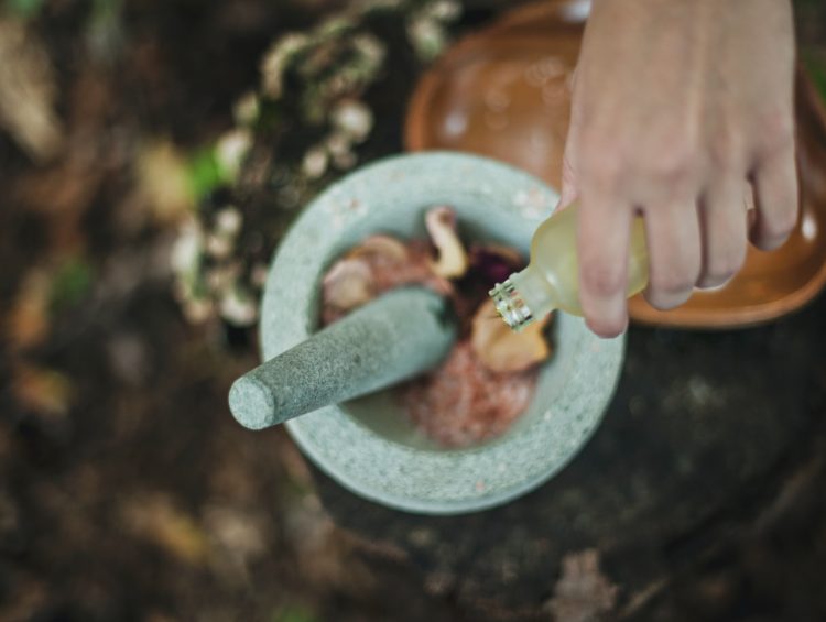 high angle photo of person pouring liquid from bottle inside mortar and pestle